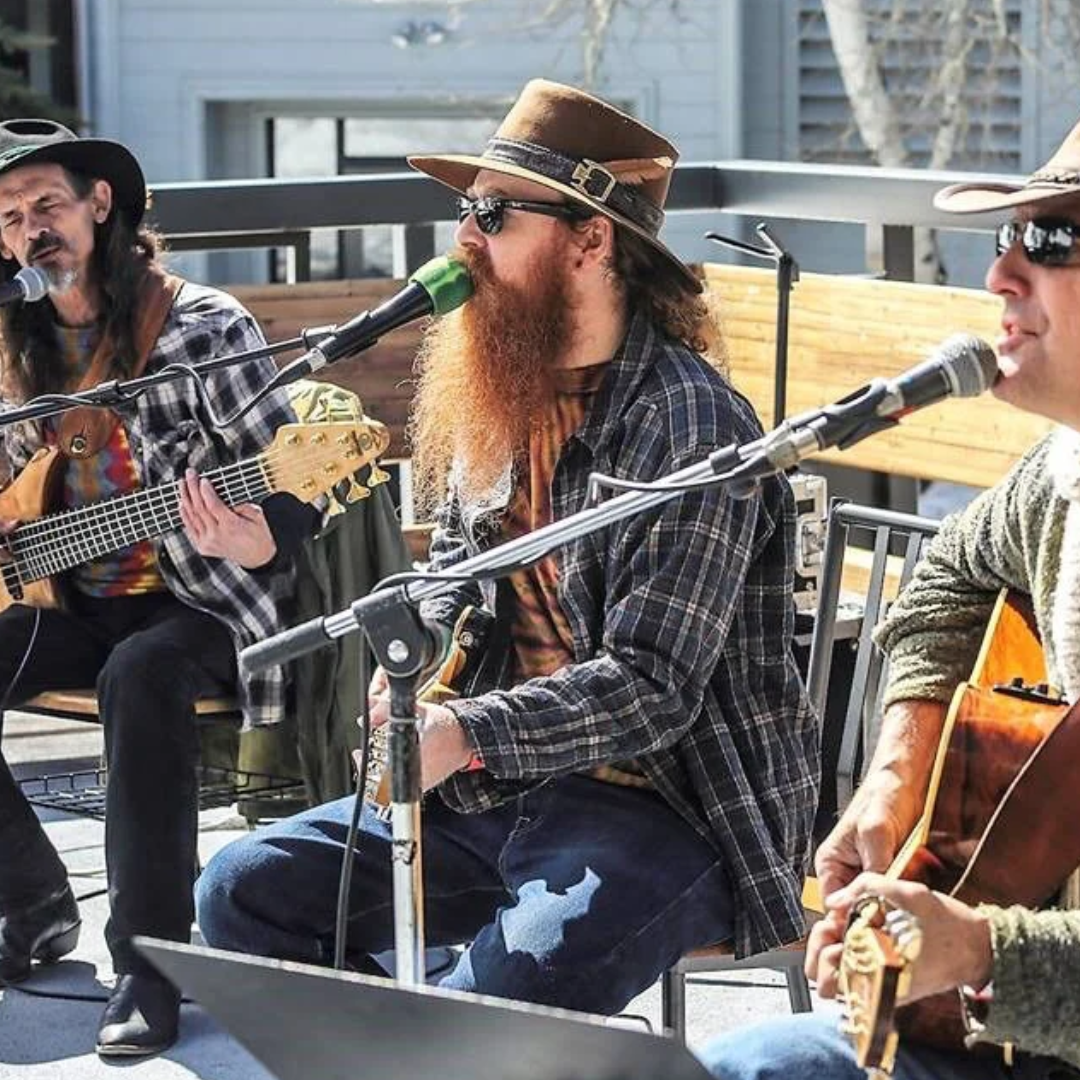 Trio playing acoustic guitars and singing outdoors in the sunshine