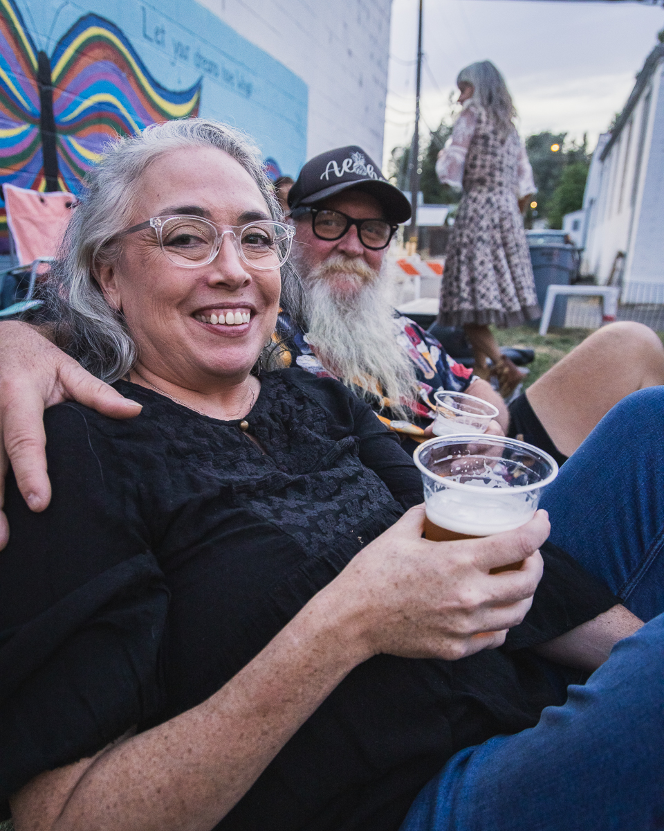 Friends smiling together with drinks at an outdoor Colfax event