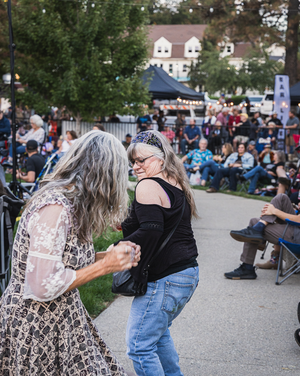 Two women dancing on the walkway while the crowd watches from lawn chairs