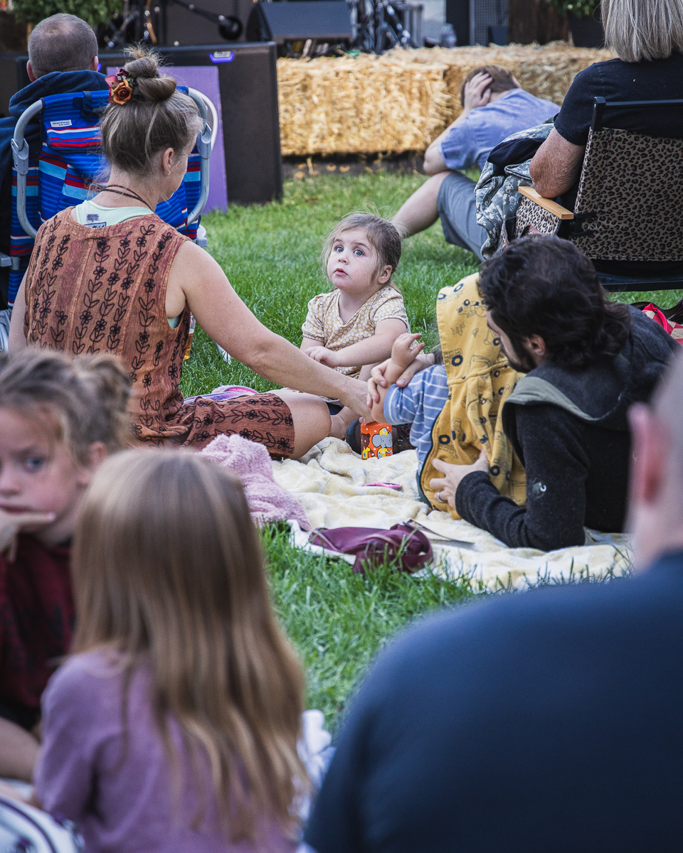 Families with young children on blankets and lawn chairs facing the stage