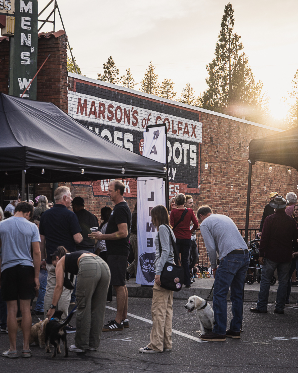 Crowd and dogs gathered at sunset beside the Marson's of Colfax brick building